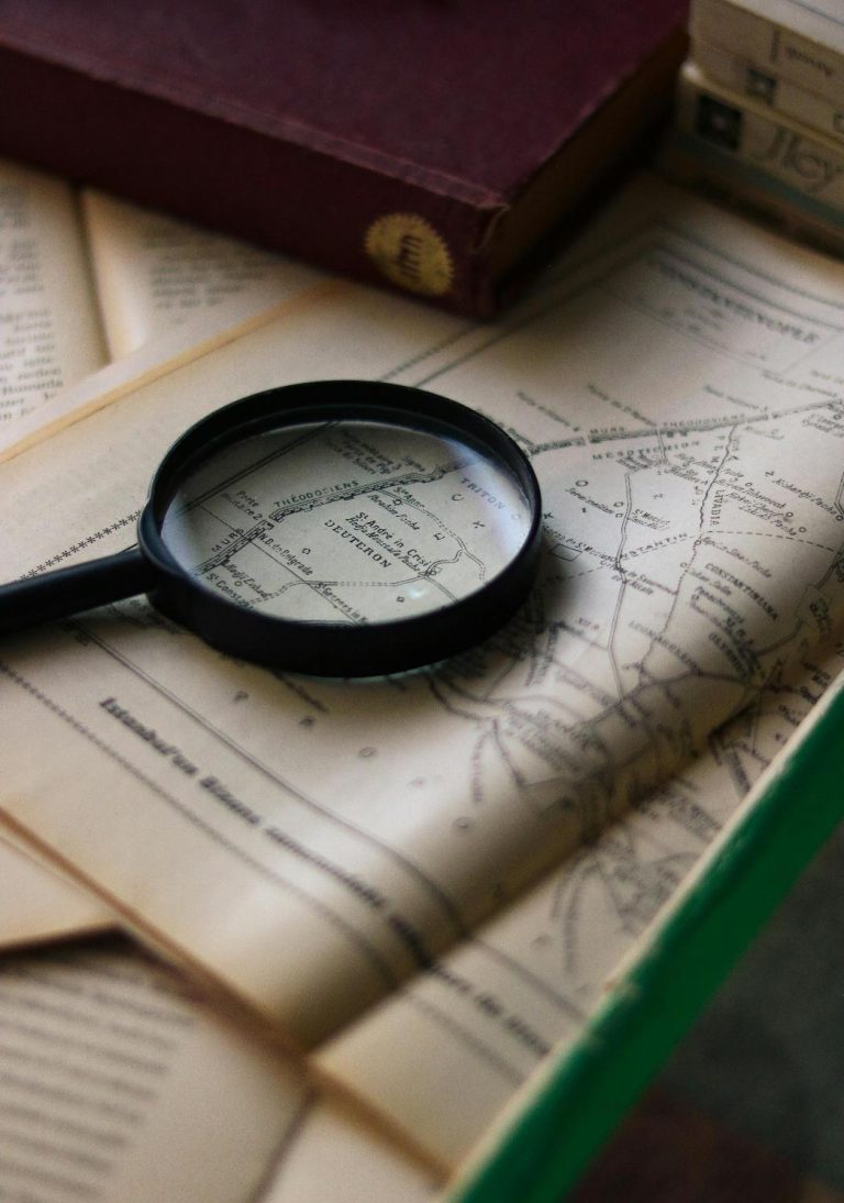 Magnifying glass over maps and property records representing title research and real estate due diligence.