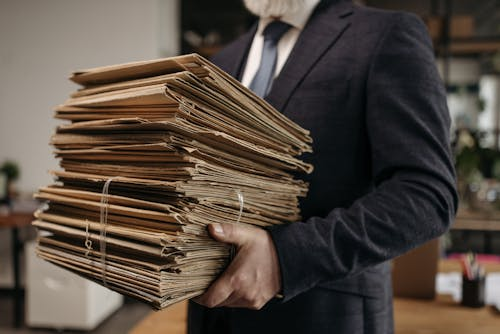 Real estate professional holding public records and property documents used for title searches, lien searches, and ownership research.