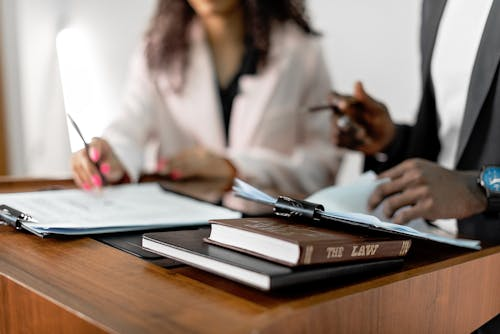 Two professionals reviewing legal documents at a desk with a law book, representing real estate litigation and property record analysis.